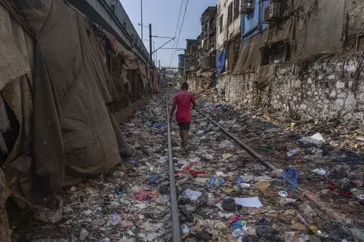 A man walks on a railway track littered with plastic and other waste materials on Earth Day in Mumbai, India, April 22, 2024. (AP Photo/Rafiq Maqbool, File)