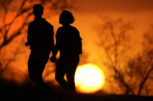 A couple walks through a park at sunset, March 10, 2021, in Kansas City, Mo. U.S. life expectancy rose in 2022 — by more than a year — after plunging two straight years at the beginning of the COVID-19 pandemic, according to a new government report released Wednesday, Nov. 29, 2023. The rise was mainly due to the waning of the pandemic in 2022, researchers said at the Centers for Disease Control and Prevention. (AP Photo/Charlie Riedel, File)