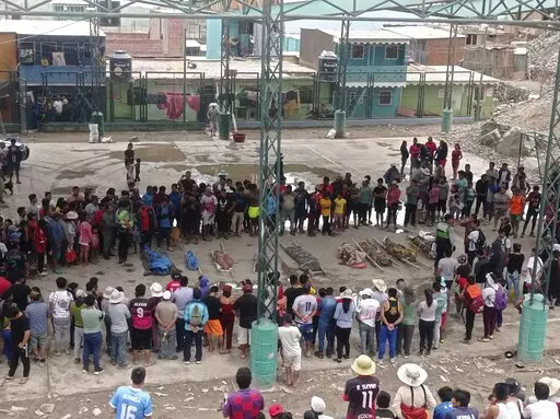 Residents stand around the bodies of persons who perished in recent landslides in Camana, Peru, Monday, Feb. 6, 2023. According to a preliminary report issued by Civil Defense, more than 30 people died as a consequence of non-stop heavy rains and landslides. (AP Photo/Ever Chambi)