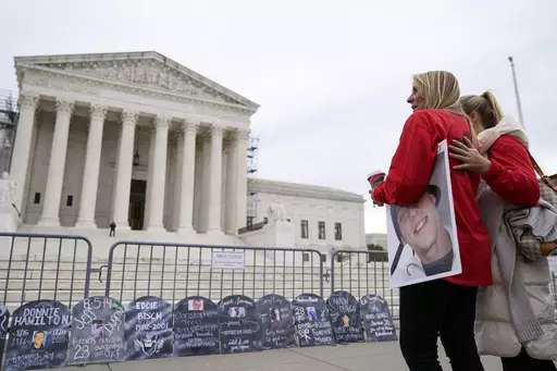 Jen Trejo holds a photo of her son Christopher as she is comforted outside the Supreme Court Monday, Dec. 4, 2023, in Washington. Her son was 32 when he died and she said about Purdue Pharma and the Sackler family, "You can't just kill my child and just pay a fine." The Supreme Court is wrestling with a nationwide settlement with OxyContin maker Purdue Pharma that would shield members of the Sackler family who own the company from civil lawsuits over the toll of opioids. (AP Photo/Stephanie Scar