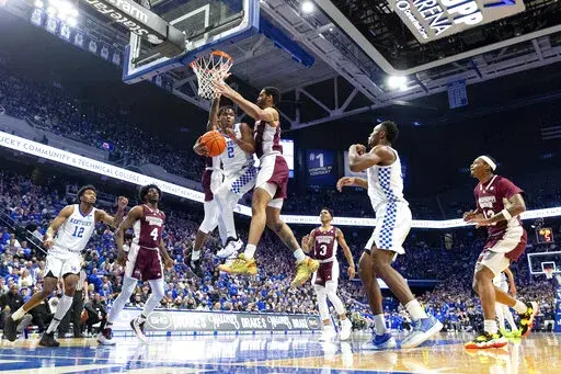 Kentucky guard Sahvir Wheeler (2) passes the ball off while being guarded by Mississippi State guard Iverson Molinar, behind Wheeler, and forward Garrison Brooks, right, during the first half of an NCAA college basketball game in Lexington, Ky., Tuesday, Jan. 25, 2022. (AP Photo/Michael Clubb)