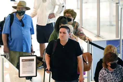 Travelers wait in a security line at Love Field in Dallas, Tuesday, April 19, 2022. The major airlines and many of the busiest airports dropped their mask requirements after a Florida judge struck down the CDC mandate and the Transportation Security Administration announced it wouldn't enforce its 2021 security directive. (AP Photo/LM Otero)