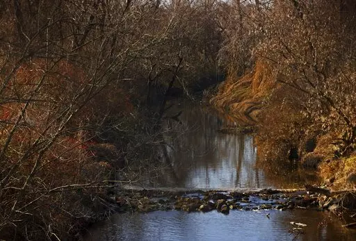 Water flows in Coldwater Creek on Thursday, Dec. 9, 2021, behind a row of homes at Belcroft Drive and Old Halls Ferry Road in Missouri's St. Louis County. Environmental investigation consultants have found significant radioactive contamination at an elementary school, which sits in the flood plain of Coldwater Creek which was contaminated by nuclear waste from weapons production during World War II. (Christian Gooden/St. Louis Post-Dispatch via AP)
