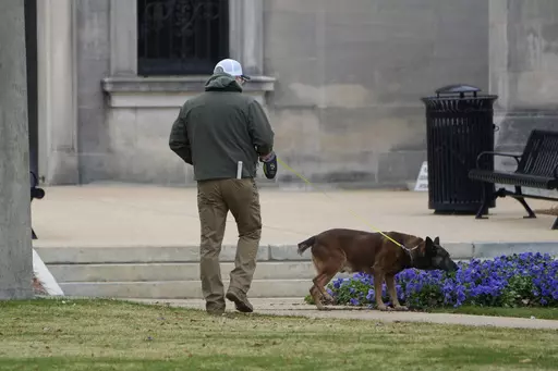 An ordinance sniffing dog patrols the Mississippi State Capitol grounds as Capitol Police respond to a bomb threat at the state building in Jackson, Miss., Wednesday morning, Jan. 3, 2024. The structure was emptied and the grounds cleared of vehicles as officers investigated. (AP Photo/Rogelio V. Solis)