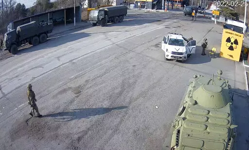 A frame grab taken by the battery-operated camera placed by Chernobyl Tour to show the company’s tourist information center near the Chernobyl nuclear power plant, shows Russian military vehicles rolling into Chernobyl, the site of the world's worst nuclear disaster, on the second day of the war, in the village of Dytyatki, Ukraine, on Friday, Feb. 25, 2022. (Yaroslav Yemelianenko/Chernobyl Tour via AP)