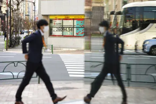 A man walks by an office building across from a securities firm showing Japan's Nikkei 225 index in Tokyo, Friday, Jan. 13, 2023. Shares advanced Friday in Asia after news that U.S. consumer inflation slowed last month pushed Wall Street benchmarks higher. (AP Photo/Hiro Komae)