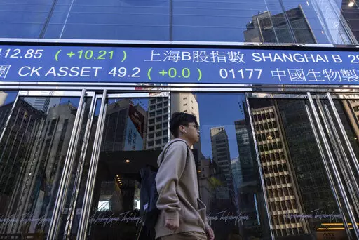 A pedestrian passes by the Hong Kong Stock Exchange electronic screen in Hong Kong, on Wednesday, March 1, 2023. Asian shares were mixed Wednesday as investors watched for upcoming earnings reports and other indicators on how inflationary pressures might be denting global growth. (AP Photo/Louise Delmotte)