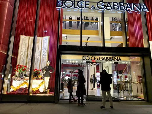 People stand outside the Dolce & Gabbana store on Fifth Avenue, Nov. 21, 2021, in New York. Dolce & Gabbana announced Monday, Jan. 31, 2022 that it will drop the use of animal fur in all its collections starting this year, and transition to eco-friendly faux fur. The Milan fashion house joins other luxury brands, including Armani, Gucci, Prada and Moncler, in adhering to guidelines set by the Fur Free Alliance, a network of animal rights groups around the world. (AP Photo/Pamela Hassell, file)