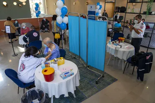 A man receives his fourth dose of the coronavirus vaccine in a private nursing home in Petah Tikva, Israel, Tuesday, Jan. 4, 2022. Even in relatively small, wealthy Israel, an early global leader against the coronavirus pandemic, the omicron variant is outpacing the government's ability to make and execute clear pandemic public policy. What once was a straightforward regimen of vaccines, testing, contact tracing and distancing for the nation of 9.3 million has splintered into a zigzag of rules t