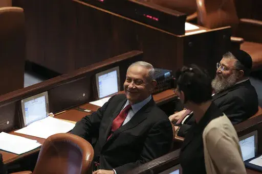 Former Israeli Prime Minister Benjamin Netanyahu smiles during a preliminary vote on a bill to dissolve parliament, at the Knesset, Israel's parliament, in Jerusalem, Wednesday, June 22, 2022. Israeli lawmakers voted in favor of dissolving parliament in a preliminary vote, setting the wheels in motion to send the country to its fifth national election in just over three years. (AP Photo/Maya Alleruzzo)