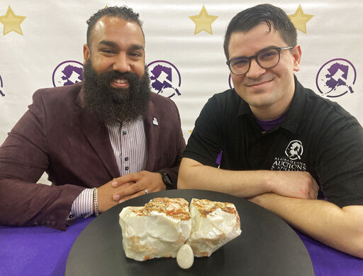 CORRECTS TO ALASKA PREMIER AUCTIONS AND APPRAISALS Dan Newman, left, the founder of Alaska Premier Auctions and Appraisals, and Nick Cline, a business partner, pose Friday, Feb. 18, 2022, in Anchorage, Alaska, with the "Americus Australis," thought to be one the largest gem-quality opals in existence. The gem will be offered at auction Sunday, Feb. 20, 2022, with an opening bid set at $125,000 (AP Photo/Mark Thiessen)