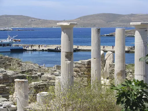 Ancient statues and columns from a millennia-old house stand just above the landing dock in the archaeological park at Delos, Greece, on May 25, 2019. The tiny island, a short boat ride from party-central Mykonos, was considered holy by ancient Greeks.  (AP Photo/Giovanna Dell’Orto)