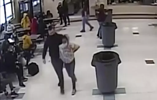 In this frame grab from surveillance video provided by the Kenosha Unified School District, an off-duty police officer escorts a 12-year-old student out of a school cafeteria following a lunchtime fight, in Kenosha, Wis., on March 4, 2022. Earlier in the video, the officer, who was working as a security guard, is shown intervening in the fight and putting his knee on the girl’s neck to restrain her. (Kenosha Unified School District via AP)