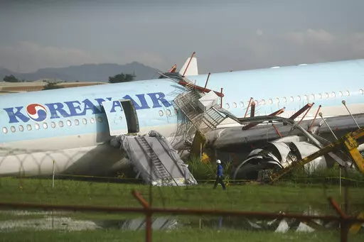 A man walks beside a damaged Korean Air plane after it overshot the runway at the Mactan-Cebu International Airport in Cebu, central Philippines early Monday Oct. 24, 2022. The Korean Air plane overshot the runway while landing in bad weather in the central Philippines late Sunday, but authorities said all 173 people on board were safe. (AP Photo/Juan Carlo De Vela)