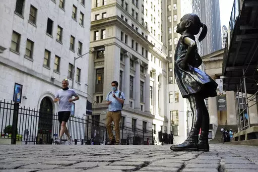 In this June 16, 2021, photo, the "Fearless Girl" statue faces the New York Stock Exchange. The 4-foot bronze "Fearless Girl" statue that was installed opposite New York City's Charging Bull in 2017 will remain in its current spot opposite the New York Stock Exchange at least until early 2023 while city officials wrestle with a permanent disposition for the popular symbol of female empowerment, a city board decided Monday, April 11, 2022. (AP Photo/Richard Drew, File)