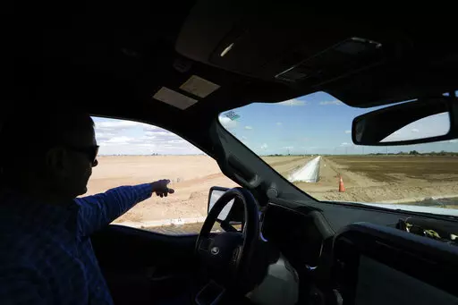Tom Brundy points to a newly built irrigation canal on one of the fields at his farm Tuesday, Feb. 28, 2023, near Calexico, Calif. Brundy, an alfalfa grower in California's Imperial Valley, thinks farmers reliant on the shrinking Colorado River can do more to save water and use it more efficiently. But one practice that's off-limits for Brundy is fallowing — leaving fields unplanted to spare the water that would otherwise irrigate crops. (AP Photo/Gregory Bull)