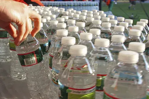 A runner grabs a bottle of water at the athlete's village prior to the start of the 116th running of the Boston Marathon, in Hopkinton, Mass., on April 16, 2012. (AP Photo/Stew Milne, File)