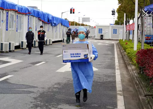 In this photo released by China's Xinhua News Agency, a worker carries a box of supplies at a makeshift hospital in Shanghai, China, Friday, April 15, 2022. Anti-virus controls that have shut down some of China's biggest cities and fueled public irritation are spreading as infections rise, hurting a weak economy and prompting warnings of possible global shockwaves. (Yang Youzong/Xinhua via AP)