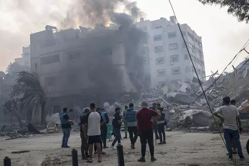 Journalists observe as Palestinians inspect the rubble of a building after it was struck by an Israeli airstrike, in Gaza City, Sunday, Oct. 8, 2023. Journalists reporting in Gaza need to worry about basic survival for themselves and their families in addition to getting out the story of a besieged population. (AP Photo/Fatima Shbair, File)