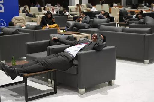 Attendees and members of the media lounge as they wait for a closing plenary session at the COP27 U.N. Climate Summit, Sunday, Nov. 20, 2022, in Sharm el-Sheikh, Egypt. (AP Photo/Peter Dejong)