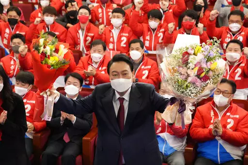 Yoon Suk Yeol, the presidential candidate of the main opposition People Power Party, who was elected South Korea's new president on Thursday, holds bouquets as he is congratulated by party's members and lawmakers at the National Assembly in Seoul, South Korea, Thursday, March 10, 2022. Yoon Suk Yeol, a conservative former top prosecutor, was elected South Korea's new president on Thursday, defeating his chief liberal rival in one of the country's most closely fought presidential elections. (AP P