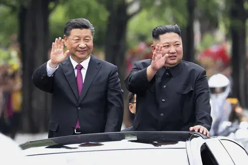 In this photo released by China's Xinhua News Agency, visiting Chinese President Xi Jinping, left, and North Korean leader Kim Jong Un wave from an open top limousine as they travel along a street in Pyongyang, North Korea, on June 20, 2019. (Ju Peng/Xinhua via AP, File)