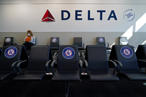 A passenger wears a face mask as she waits in a socially-distance area for a Delta Airlines flight, Wednesday, Feb. 3, 2021, at Hartsfield-Jackson International Airport in Atlanta.  Delta Air Lines will start paying flight attendants during the time that passengers are boarding. That's a first for a major U.S. airline. Flight attendants in the U.S. generally don't begin getting paid until the doors close after boarding. Delta said Tuesday, April 26, 2022, that the change will take effect in June