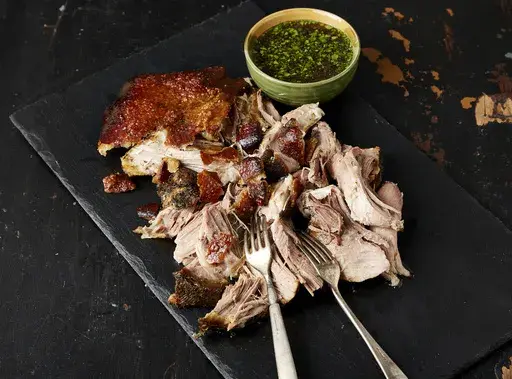 This image released by Milk Street shows a recipe for Puerto Rican slow-cooked pork roast. (Milk Street via AP)
