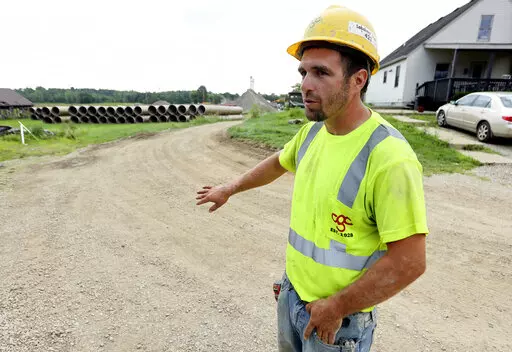 Taylor Purdy, a pipe layer with Complete General Construction, answers questions about his experience working around the new Intel semiconductor manufacturing plant construction site in Johnstown, Ohio, during an interview near the site Friday, Aug. 5, 2022. Purdy spends his days in trenches helping position storm and sanitary sewers and waterlines. Overtime is plentiful as deadlines approach. (AP Photo/Paul Vernon)