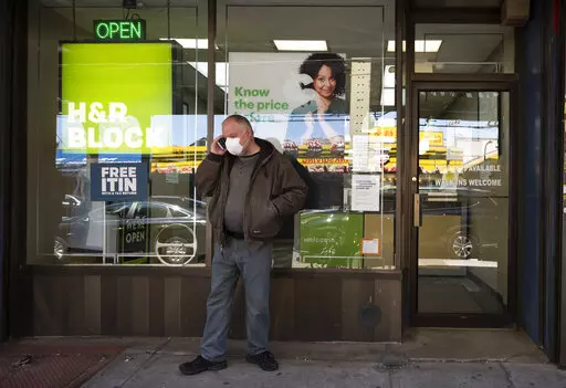 A man waits outside a H&R Block tax preparation office on Monday, April 6, 2020, in the Brooklyn borough of New York. Tax season is here again. Whether you do your taxes by yourself, go to a tax clinic or hire a professional, navigating the tax system can be complicated. (AP Photo/Mark Lennihan, File)
