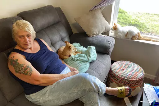 Janna Sharrett relaxes at home on a day off from her job as a full-time customer service rep for a contact lens and eyeglass company, on Tuesday, Nov. 1, 2022, in Grove City, Ohio. Sharrett earns $14.94 an hour but pays just $695 a month in rent thanks to the affordable housing apartment developed by a local nonprofit to expand the number of low-rent options in central Ohio. A shortage of housing of all kinds in the region is raising concerns as Intel Corp. develops a $20 billion project expecte