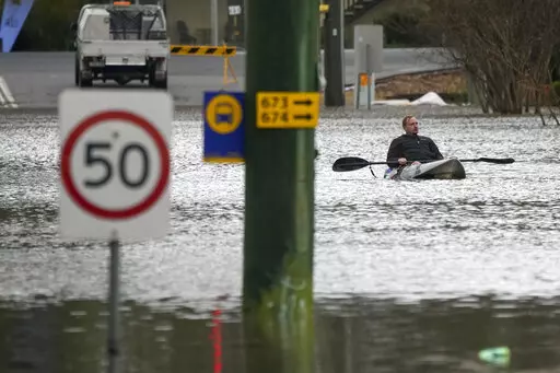 A man paddles his kayak through a flooded street at Windsor on the outskirts of Sydney, Australia, Tuesday, July 5, 2022. Hundreds of homes have been inundated in and around Australia's largest city in a flood emergency that was impacting 50,000 people, officials said Tuesday. (AP Photo/Mark Baker)