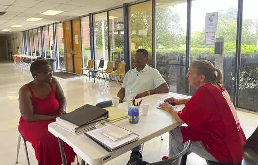 Veronique Daniels, left, speaks to Red Cross volunteers at a temporary shelter for people displaced by central Mississippi flooding, in Jackson, Miss, Sunday, Aug. 28, 2022. Daniels has been homeless for three months and three weeks. She had been sleeping on her mother's back porch when residents in the neighborhood were advised to evacuate. (AP Photo/Michael Goldberg)