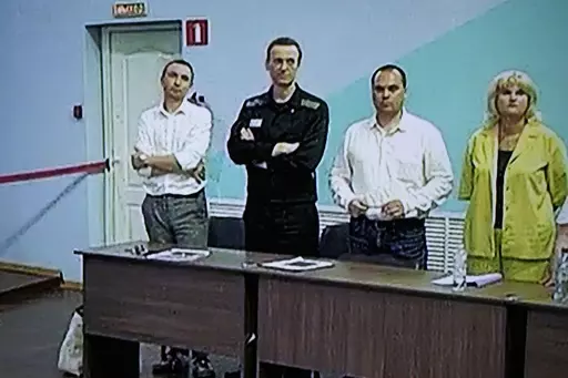 FILE Russian opposition leader Alexei Navalny, 2nd left, and his lawyers Alexander Fedulov, left, Olga Mikhailova, right, and Vadim Kobzev, second right, are seen on a TV screen standing among his lawyers, as he appears in a video link provided by the Russian Federal Penitentiary Service, during a hearing in the colony, in Melekhovo, Vladimir region, about 260 kilometers (163 miles) northeast of Moscow, Russia, on Friday, Aug. 4, 2023. Russian authorities on Friday, Oct. 13, 2023 searched the ho