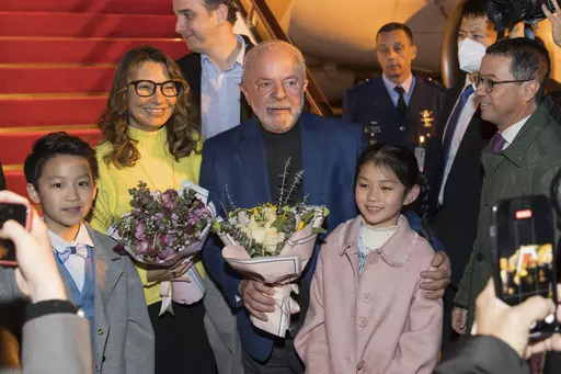In this photo released by Xinhua News Agency, Brazilian President Luiz Inacio Lula da Silva, center, and first lady Rosangela Silva, second left, receive flowers presented by children from the Shanghai Children's Palace of the China Welfare Institute upon arrival in Shanghai, China on Wednesday, April 12, 2023. Lula was in the Chinese financial hub of Shanghai on Thursday in a bid to boost ties with the South American giant's biggest trade partner and win political support for attempts to mediat