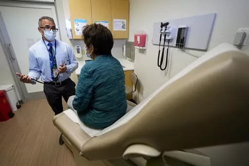 Nurse practitioner Anthony Carano speaks with a patient at the Mountain Park Health Center, Thursday, March 30, 2023, in Phoenix. As heat waves fueled by climate change arrive earlier, grow more intense and last longer, people over 60 who are more vulnerable to high temperatures are increasingly at risk of dying from heat-related causes. Heat related deaths are challenging community health systems, utility companies, apartment managers and local governments to better protect older people when te
