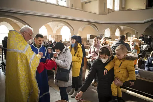 Members of the Ukrainian Orthodox community, who have found shelter for their church service in an evangelical church, and refugees from Ukraine celebrate a church service and pray for peace in Berlin, Sunday, March 20, 2022. (AP Photo/Steffi Loos)