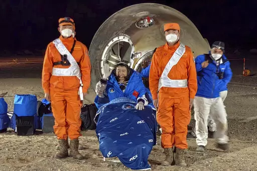 In this photo released by Xinhua News Agency, astronaut Chen Dong waves as he sits outside the re-entry capsule of the Shenzhou-14 manned space mission after it lands successfully at the Dongfeng landing site in northern China's Inner Mongolia Autonomous Region, Sunday, Dec. 4, 2022. Three Chinese astronauts landed in a northern desert on Sunday after six months working to complete construction of the Tiangong station, a symbol of the country's ambitious space program, state TV reported. (Li Gan