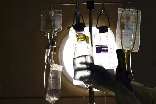 A nurse checks on IV fluids while talking to a COVID-19 patient at Providence Holy Cross Medical Center in Los Angeles, Dec. 13, 2021. When the end of the COVID pandemic comes, it could create major disruptions for U.S. health care. (AP Photo/Jae C. Hong, File)