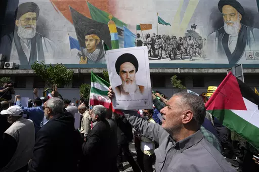 Iranian worshippers walk past a mural showing the late revolutionary founder Ayatollah Khomeini, right, Supreme Leader Ayatollah Ali Khamenei, left, and Basij paramilitary force, as they hold posters of Ayatollah Khomeini and Iranian and Palestinian flags in an anti-Israeli gathering after Friday prayers in Tehran, Iran, April 19, 2024. This month's unprecedented direct attacks between Iran and Israel are revealing deeper insights into both militaries. Experts say Friday's apparent precision str