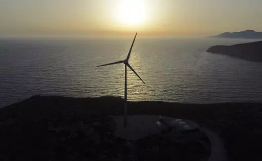 The sun sets behind a wind turbine on the Aegean Sea island of Tilos, southeastern Greece, Monday, May 9, 2022. When deciding where to test green tech, Greek policymakers picked the remotest point on the map, tiny Tilos. Providing electricity and basic services, and even access by ferry is all a challenge for this island of just 500 year-round inhabitants. It's latest mission: Dealing with plastic. (AP Photo/Thanassis Stavrakis)