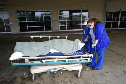 Medical staff prepare to move the body of a deceased COVID-19 patient to a funeral home van at the Willis-Knighton Medical Center in Shreveport, La., Wednesday, Aug. 18, 2021. Data released by the Centers for Disease Control and Prevention in April 2022 confirms that 2021 was the deadliest year in U.S. history. (AP Photo/Gerald Herbert, File)