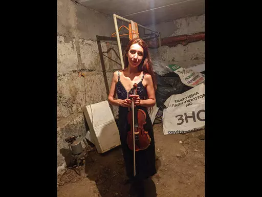 CORRECTS SPELLING OF NAME  Vera Lytovchenko holds her violin as she poses for a photo in a basement of an apartment building in Kharkiv, Ukraine, Sunday March 6, 2022. Lytovchenko is Ukraine's cellar violinist, who has become an internet icon of resilience as images of her playing in the basement bomb shelter have inspired an international audience via social media. (Vera Lytovchenko via AP)